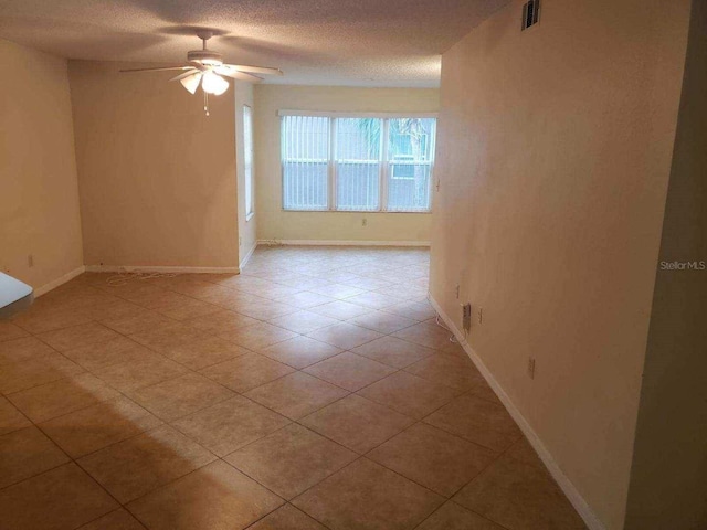 tiled empty room featuring a textured ceiling and ceiling fan