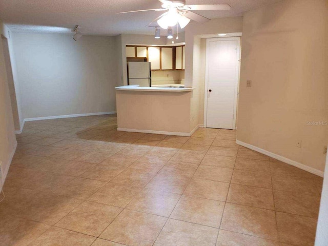 kitchen with ceiling fan, white refrigerator, light tile patterned floors, and a textured ceiling