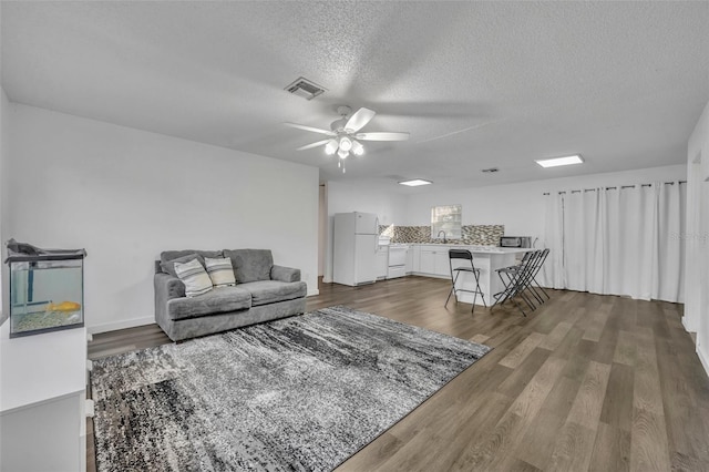 living room featuring ceiling fan, dark hardwood / wood-style floors, sink, and a textured ceiling