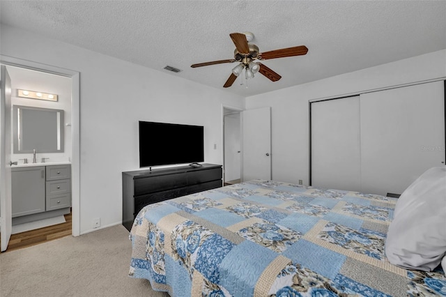 carpeted bedroom featuring ceiling fan, a textured ceiling, connected bathroom, and a closet