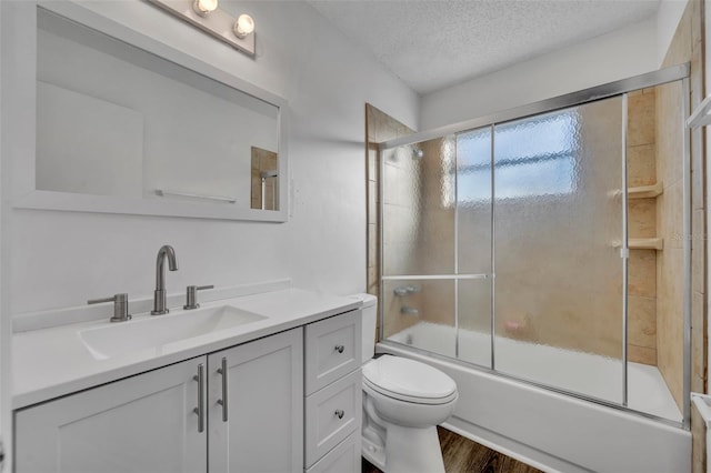 full bathroom featuring enclosed tub / shower combo, a textured ceiling, toilet, vanity, and hardwood / wood-style flooring