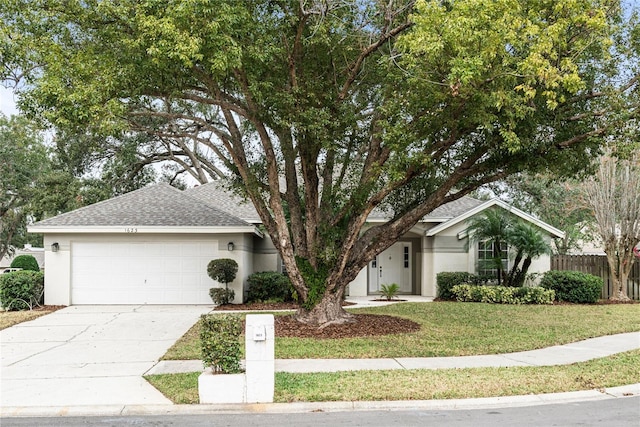 single story home featuring stucco siding, a front lawn, driveway, fence, and a shingled roof