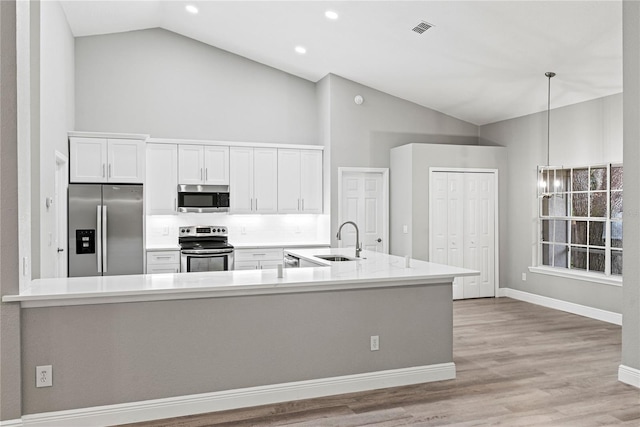 kitchen with stainless steel appliances, sink, decorative light fixtures, high vaulted ceiling, and white cabinetry