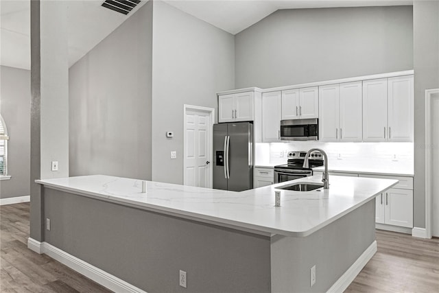 kitchen with light stone countertops, appliances with stainless steel finishes, white cabinetry, and sink