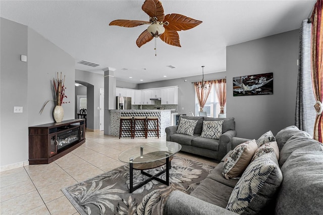 living room featuring light tile patterned floors and ceiling fan with notable chandelier