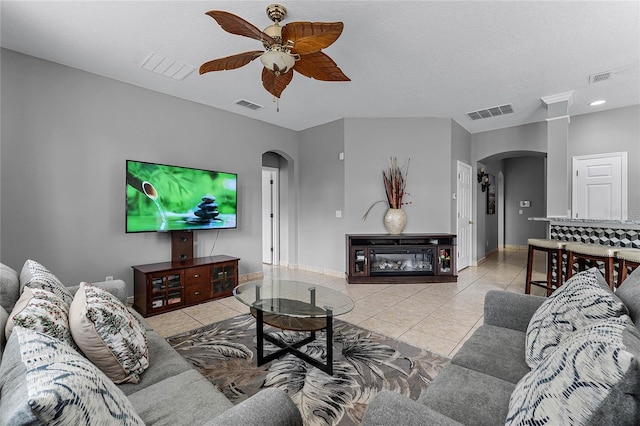 living room with a textured ceiling, ceiling fan, and light tile patterned flooring