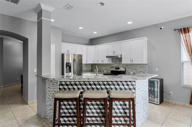 kitchen featuring tasteful backsplash, white cabinetry, a breakfast bar, and appliances with stainless steel finishes