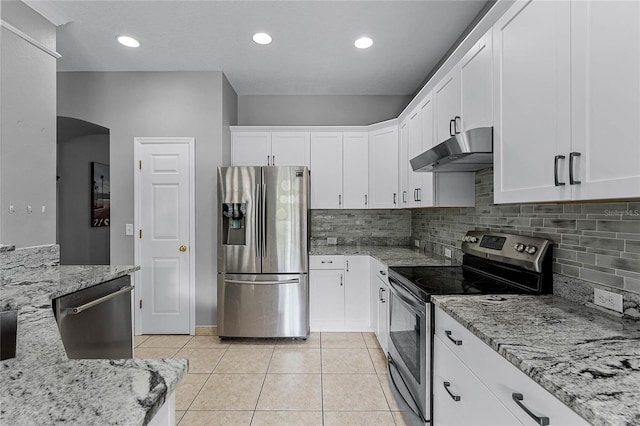 kitchen featuring light stone countertops, backsplash, stainless steel appliances, light tile patterned floors, and white cabinetry