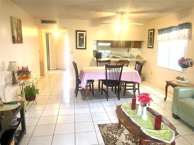 dining area with light tile patterned floors, a textured ceiling, ceiling fan, and sink