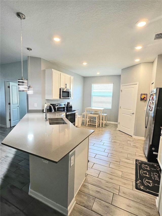 kitchen with sink, hanging light fixtures, stainless steel appliances, kitchen peninsula, and white cabinets