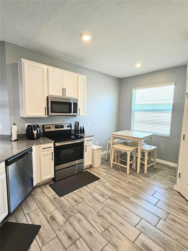 kitchen with white cabinets, a textured ceiling, and appliances with stainless steel finishes