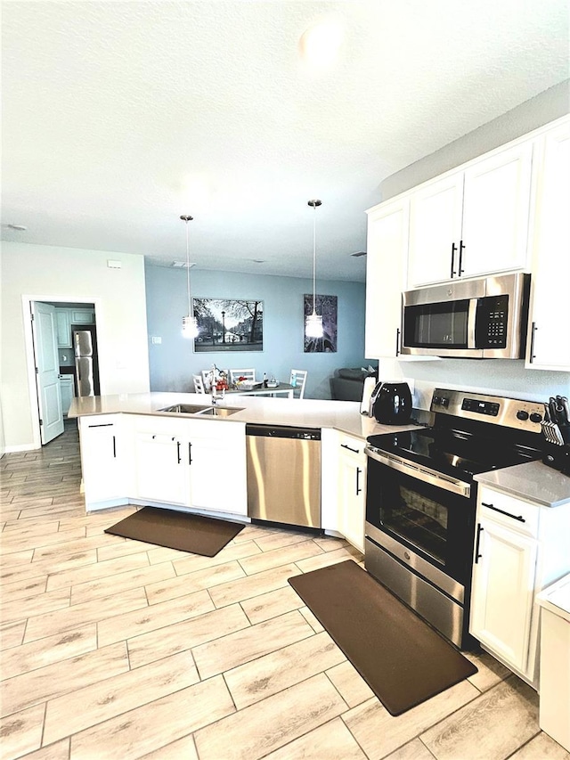 kitchen with kitchen peninsula, white cabinetry, pendant lighting, and appliances with stainless steel finishes