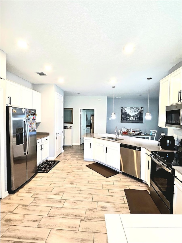 kitchen featuring hanging light fixtures, white cabinets, stainless steel appliances, and sink