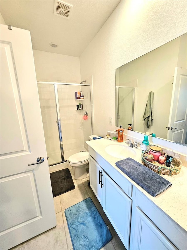 bathroom with tile patterned flooring, vanity, toilet, and a shower with door