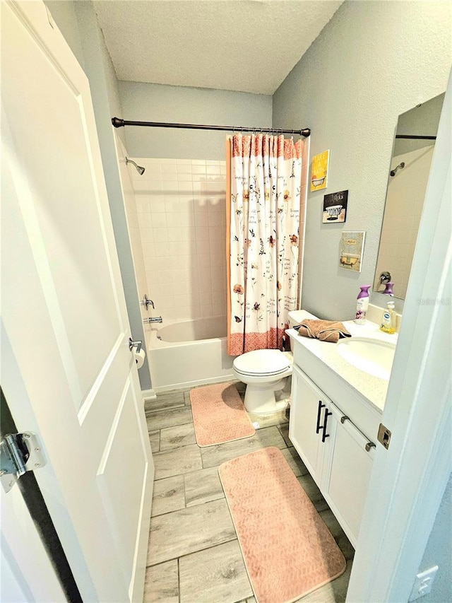 full bathroom featuring a textured ceiling, vanity, shower / tub combo, and toilet