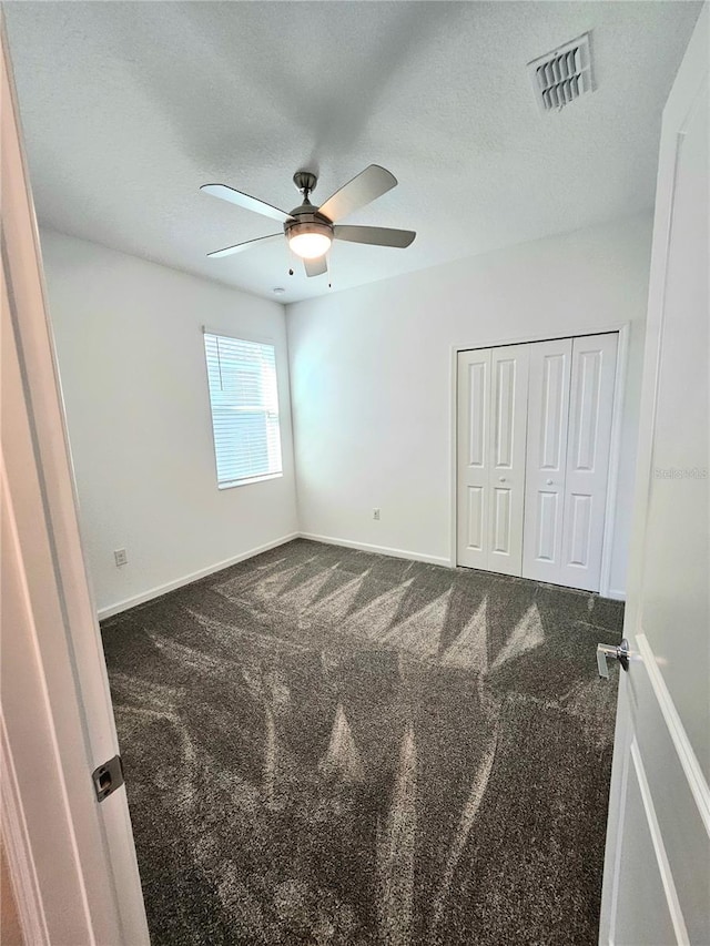 carpeted spare room with a textured ceiling and ceiling fan