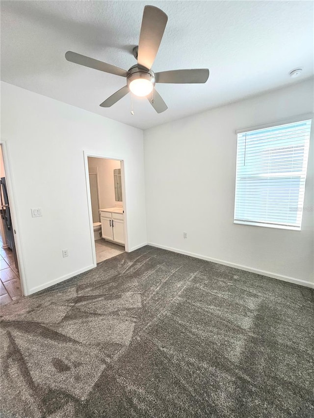 empty room with ceiling fan and dark carpet