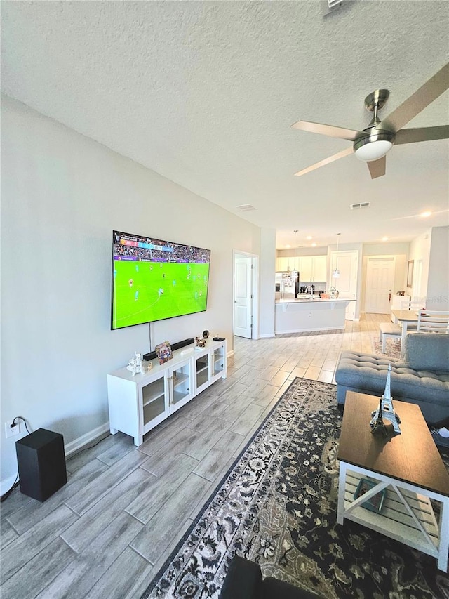 living room featuring ceiling fan and a textured ceiling