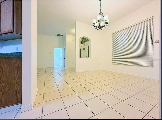 tiled empty room with a notable chandelier