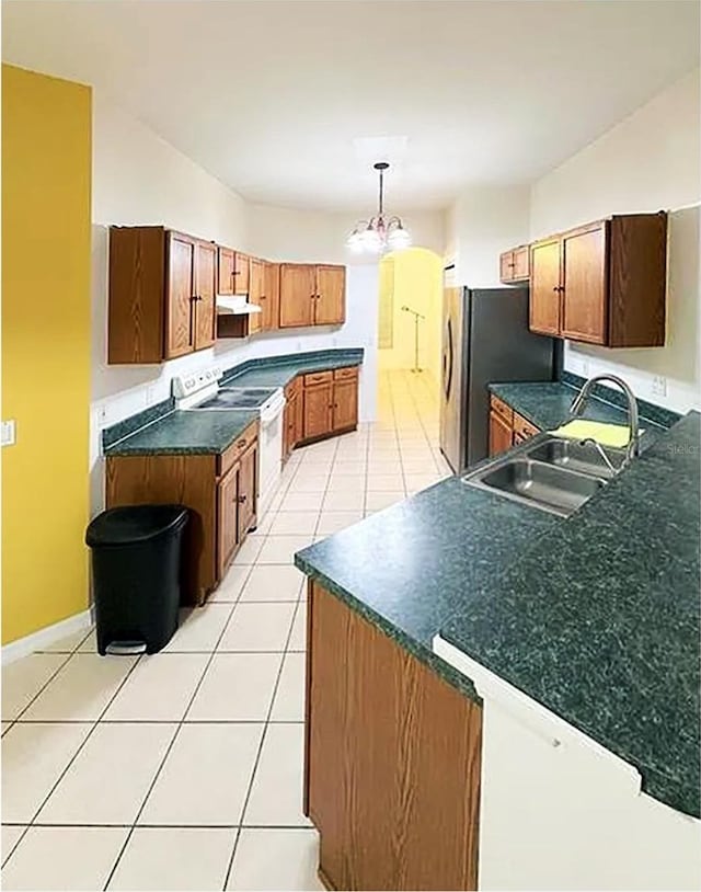 kitchen with white electric range, sink, decorative light fixtures, light tile patterned floors, and stainless steel fridge