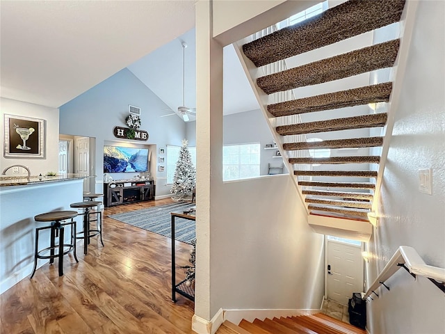 staircase featuring ceiling fan, hardwood / wood-style floors, and vaulted ceiling