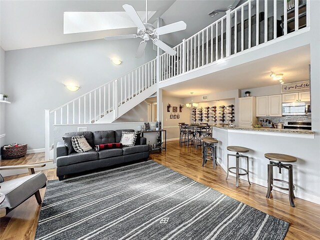 5269 Wellington Park Cir Unit 23, Orlando, FL 32839 - living room featuring high vaulted ceiling, light wood-style floors, a ceiling fan, stairway, and a skylight
