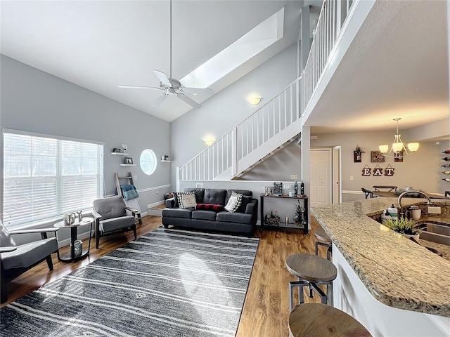 living room with ceiling fan with notable chandelier, dark hardwood / wood-style flooring, high vaulted ceiling, and sink