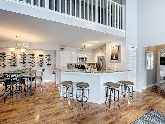 5269 Wellington Park Cir Unit 23, Orlando, FL 32839 - kitchen with appliances with stainless steel finishes, light wood-style floors, stone countertops, a kitchen bar, and a high ceiling