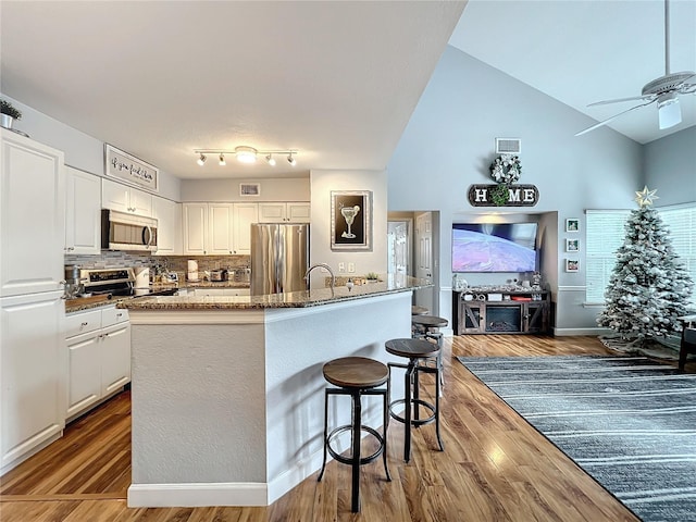 5269 Wellington Park Cir Unit 23, Orlando, FL 32839 - kitchen featuring stainless steel appliances, wood finished floors, white cabinets, a breakfast bar, and a ceiling fan