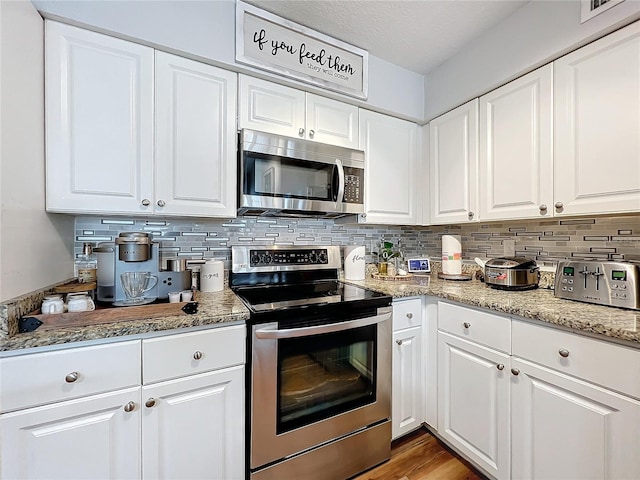 kitchen with backsplash, white cabinets, and stainless steel appliances