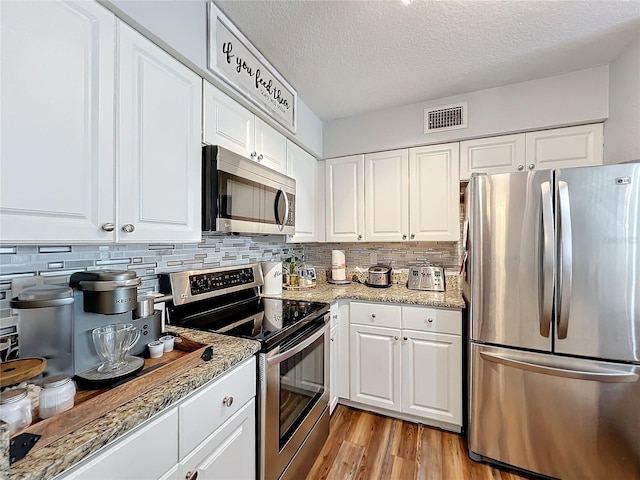 5269 Wellington Park Cir Unit 23, Orlando, FL 32839 - kitchen featuring appliances with stainless steel finishes, tasteful backsplash, white cabinetry, and a textured ceiling