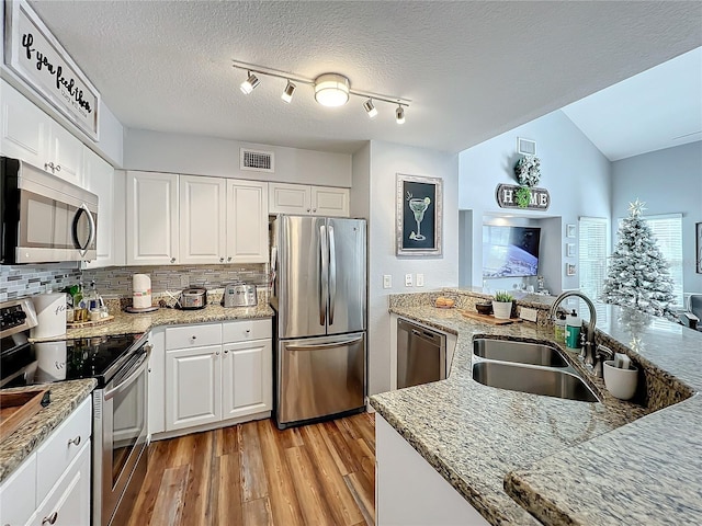 5269 Wellington Park Cir Unit 23, Orlando, FL 32839 - kitchen featuring stainless steel appliances, light wood-style floors, white cabinetry, tasteful backsplash, and a textured ceiling