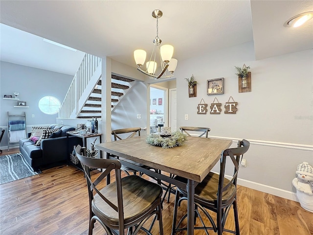 dining area with hardwood / wood-style floors and an inviting chandelier