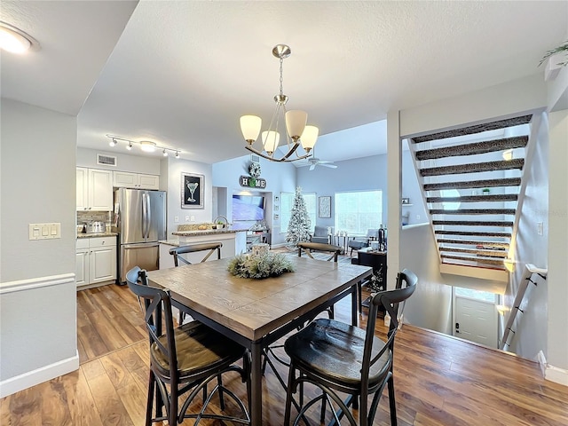 dining area featuring ceiling fan with notable chandelier and light wood-type flooring