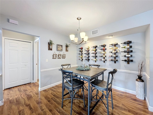 dining room with dark wood-type flooring and a notable chandelier