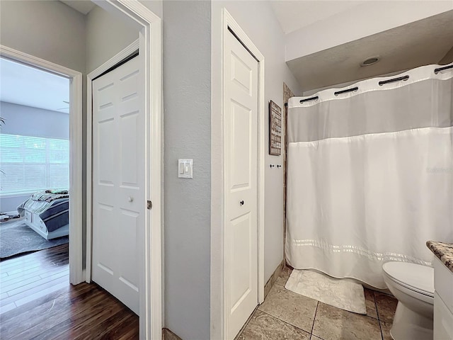 bathroom with a shower with curtain, wood-type flooring, and toilet