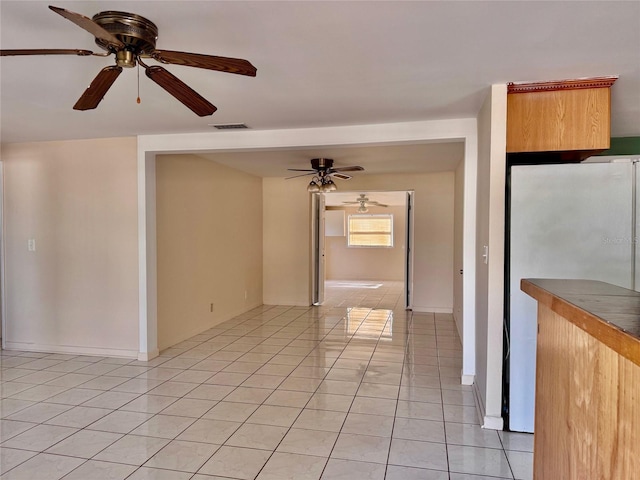 tiled empty room featuring ceiling fan