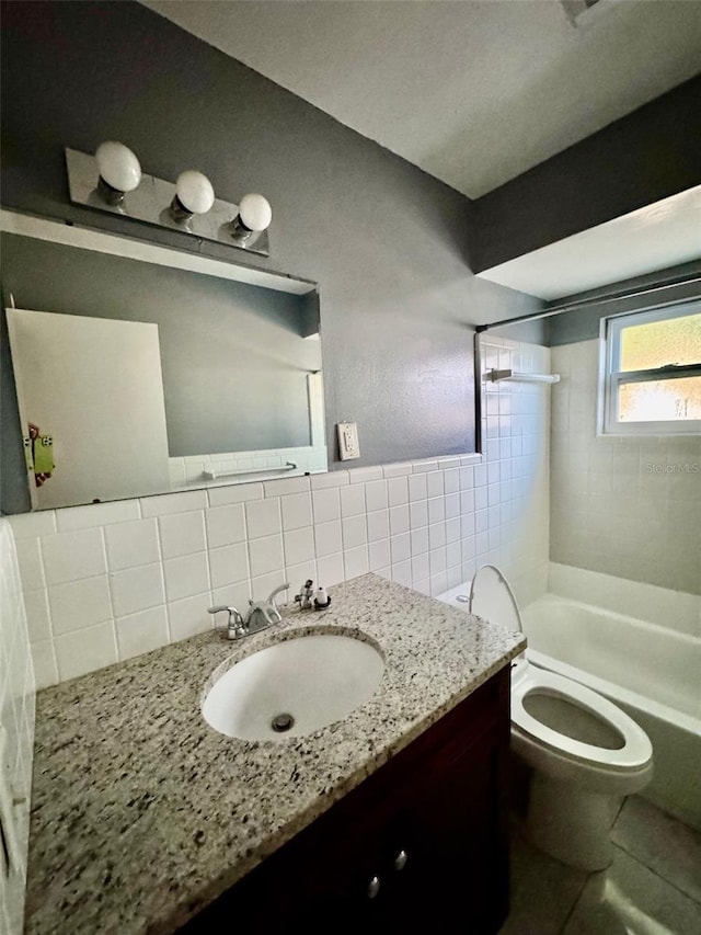 full bathroom with decorative backsplash, vanity, tiled shower / bath combo, tile walls, and toilet