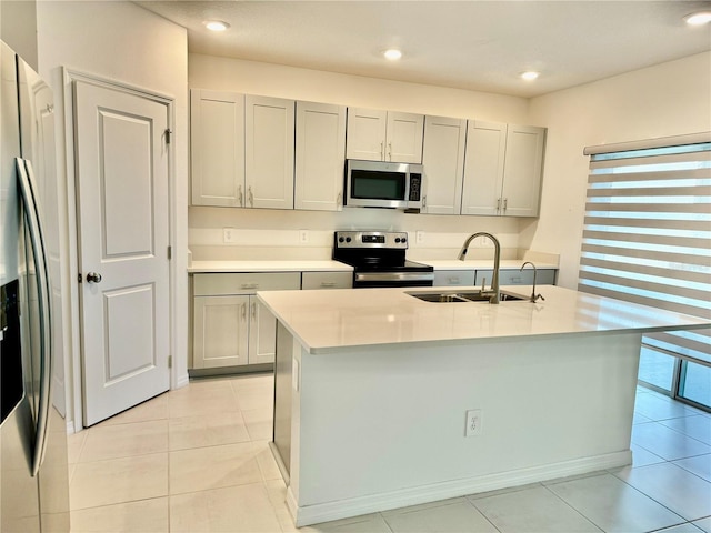 kitchen featuring gray cabinets, light countertops, appliances with stainless steel finishes, light tile patterned flooring, and a sink