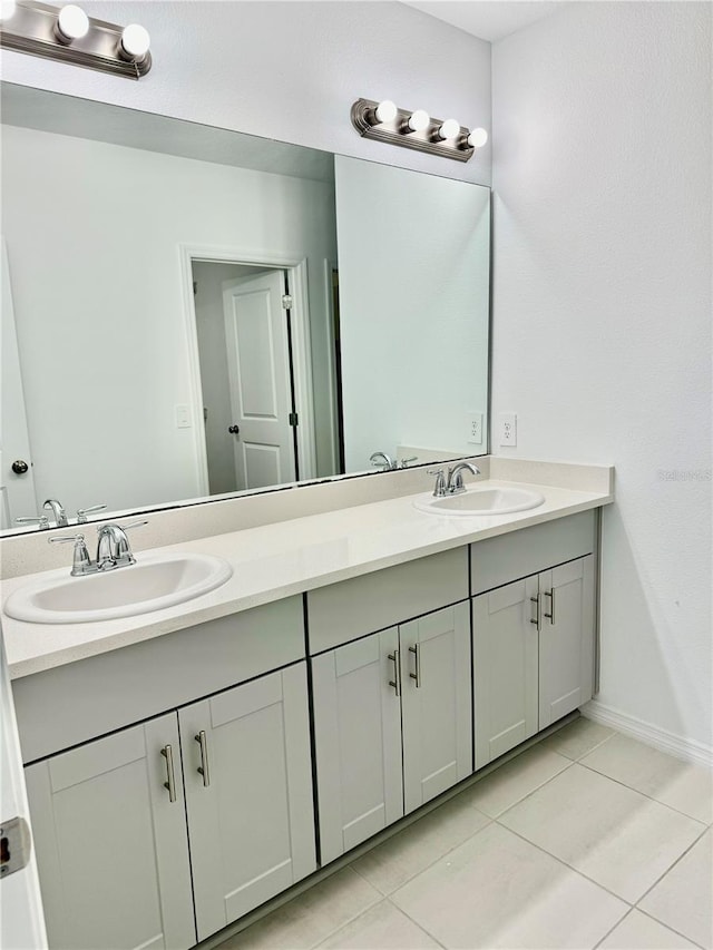 full bath featuring double vanity, tile patterned flooring, a sink, and baseboards