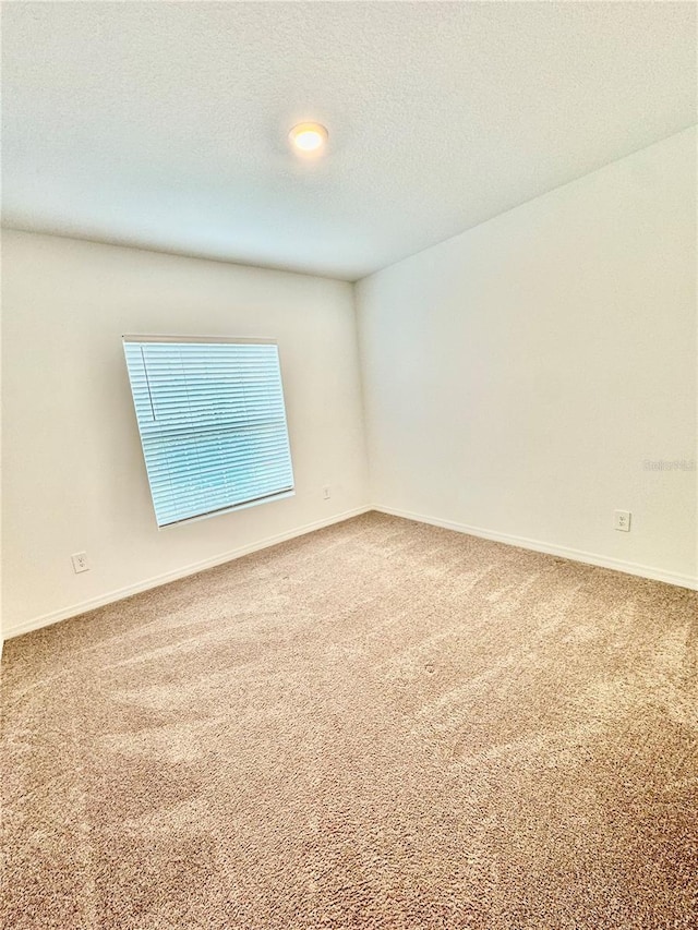 carpeted spare room with baseboards and a textured ceiling