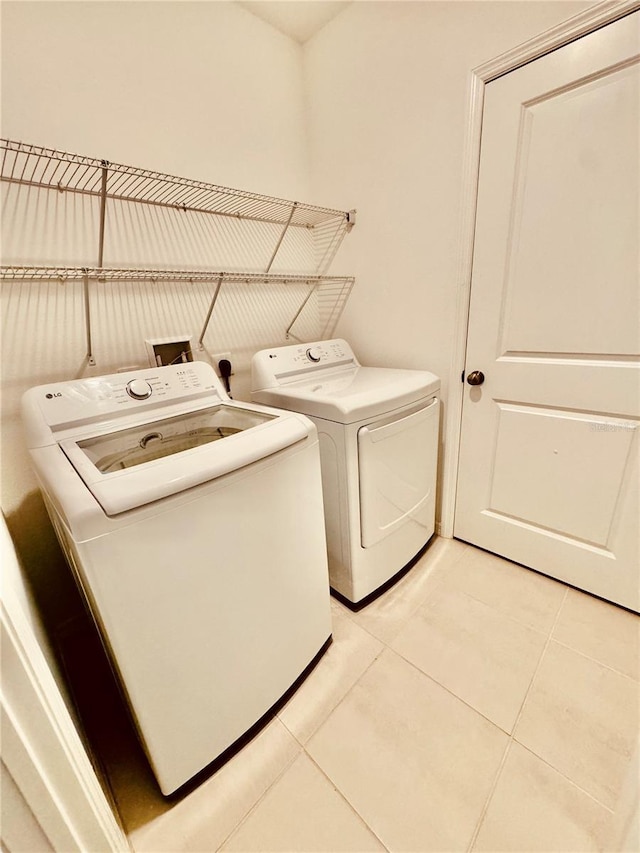 clothes washing area with laundry area, separate washer and dryer, and light tile patterned flooring