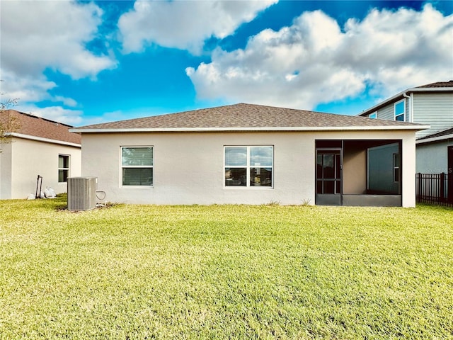 rear view of house with a yard, stucco siding, a shingled roof, a sunroom, and cooling unit