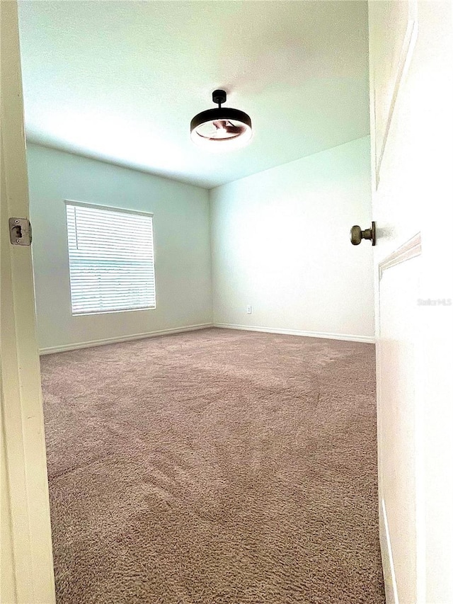 carpeted spare room featuring baseboards