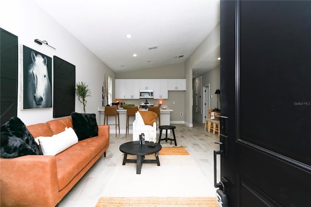 living room with light hardwood / wood-style floors and vaulted ceiling