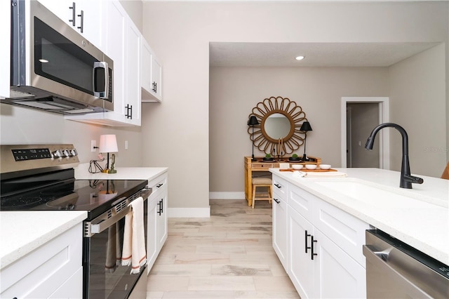 kitchen featuring white cabinetry, sink, stainless steel appliances, and light wood-type flooring