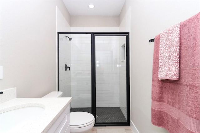 bathroom with tile patterned floors, a shower with door, vanity, and toilet