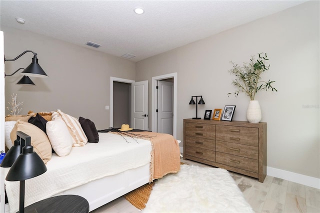 bedroom featuring light wood-type flooring and a textured ceiling