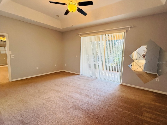 spare room featuring carpet flooring, a tray ceiling, and ceiling fan