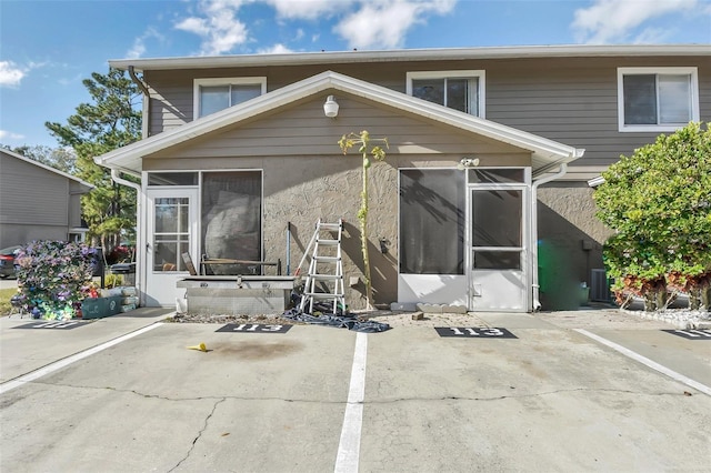 rear view of house with central air condition unit, a patio area, and a sunroom